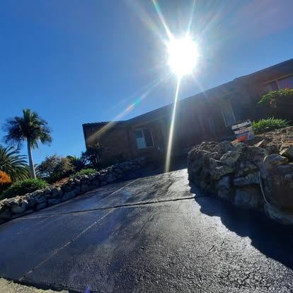 Dark sealed concrete driveway running up to a brick home