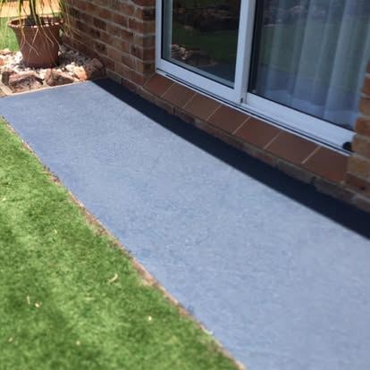 Light coated concrete path running alongside a lawn